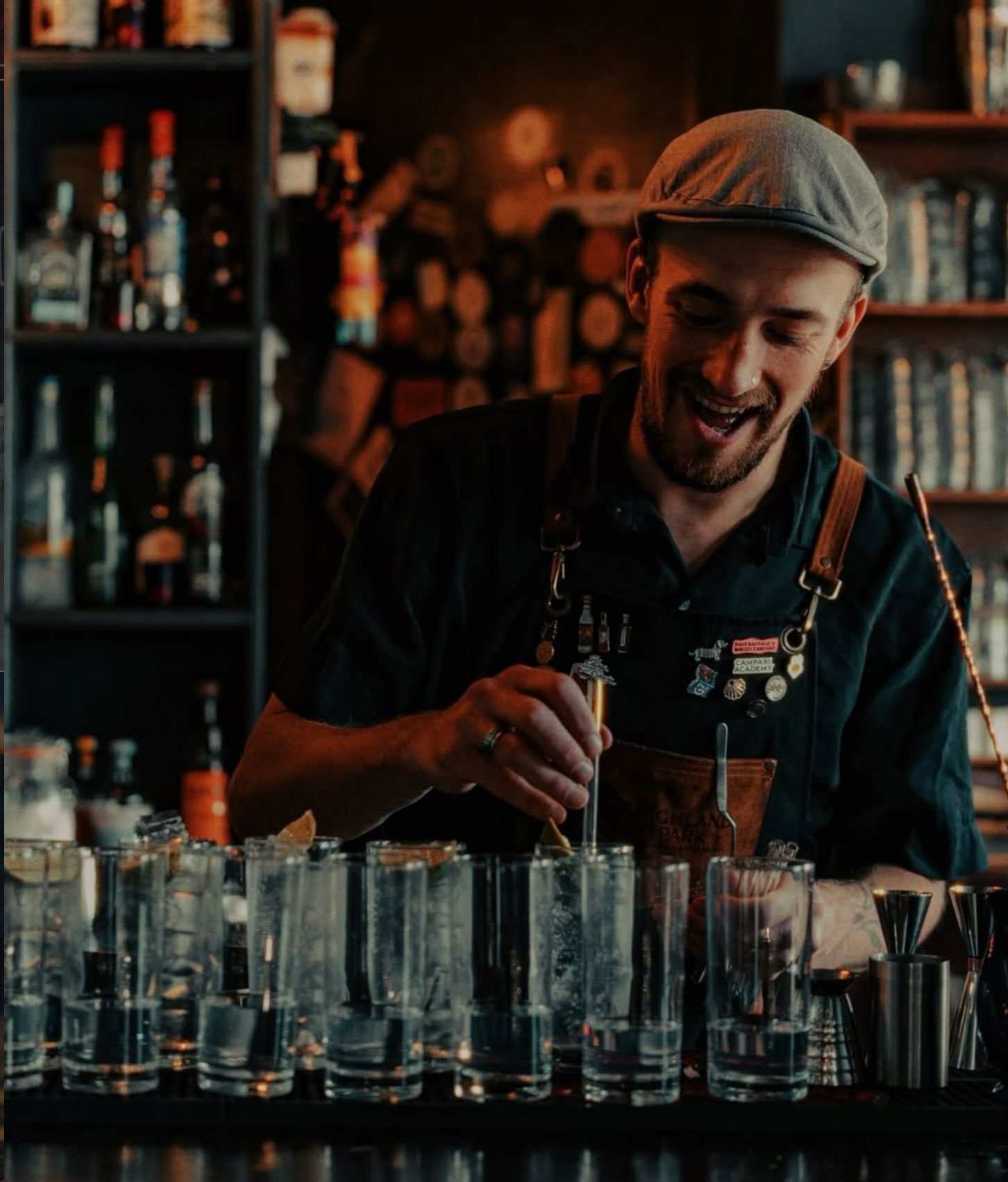 A bartender preparing a row of cocktails behind the bar at The Milk Thistle